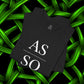 Folded black As Above So Below IYKYK t-shirt on glowing green abstract background.