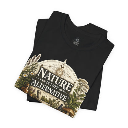 Folded black Nature Is Not Alternative t-shirt showing close-up botanical apothecary graphic with herbs and mushroom artwork.