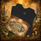 Folded black The First Pharmacy Was a Garden t-shirt with close-up botanical artwork, herbs, mushrooms, and apothecary design.