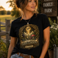 Woman wearing You Can’t Patent God’s Garden black t-shirt in a sunny farm setting with flowers and rustic decor.