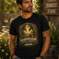 Man wearing You Can’t Patent God’s Garden black t-shirt in a rustic farm setting with a Faith Family Farm sign.